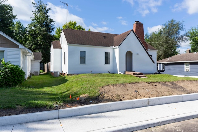 view of front of property featuring cooling unit and a front lawn