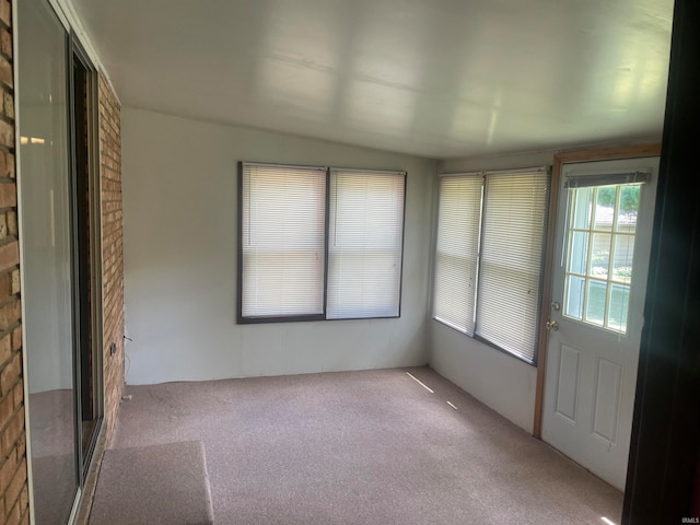 empty room featuring carpet flooring and brick wall