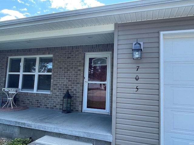 view of exterior entry with a garage and a porch