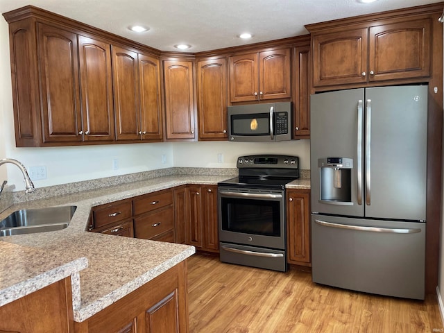 kitchen with sink, stainless steel appliances, and light wood-type flooring