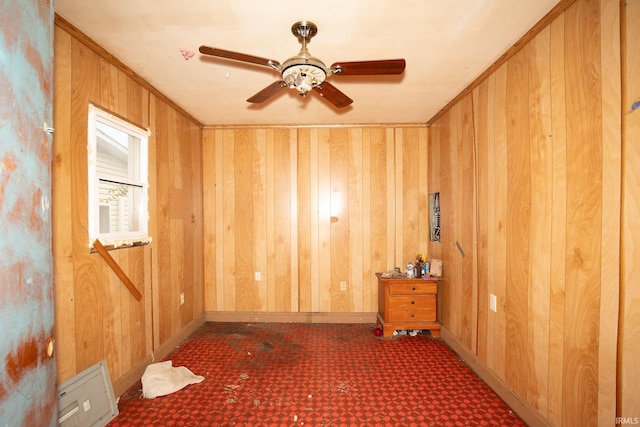 spare room featuring wood walls, carpet, and ceiling fan