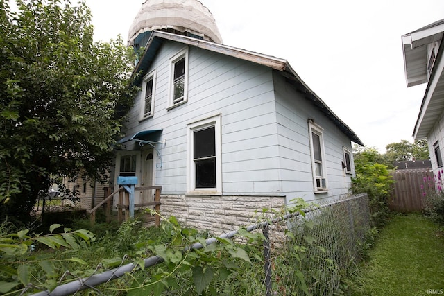 back of house with stone siding and fence