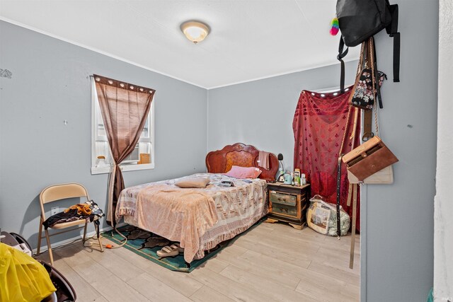 bedroom with light hardwood / wood-style flooring and crown molding