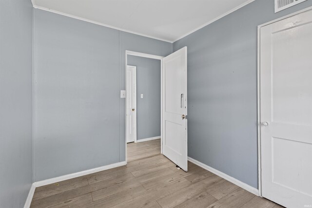 spare room featuring light wood-type flooring and ornamental molding