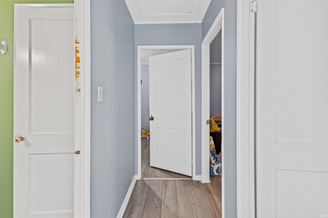 corridor with light wood-type flooring and ornamental molding