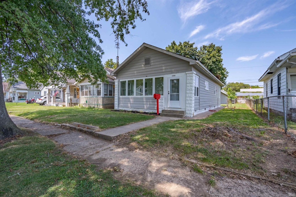 view of front facade with entry steps, fence, and a front lawn