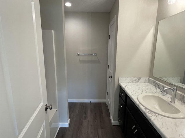 bathroom with a textured ceiling, vanity, and wood-type flooring