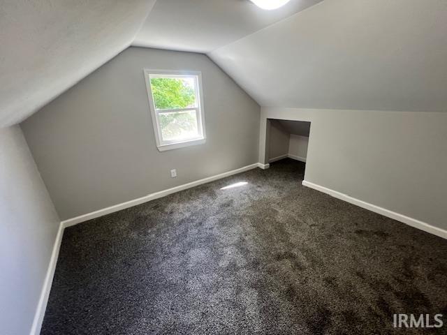 additional living space with vaulted ceiling and dark carpet