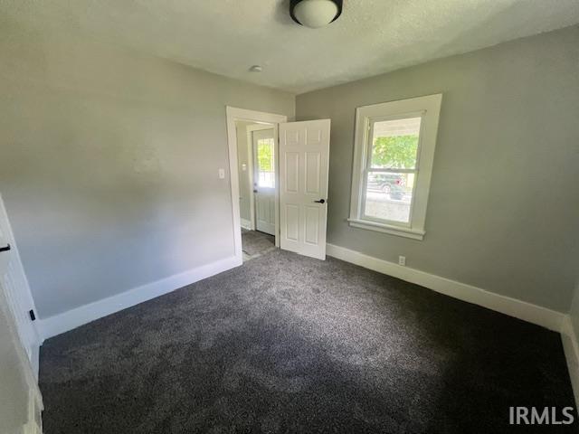 unfurnished bedroom featuring dark carpet