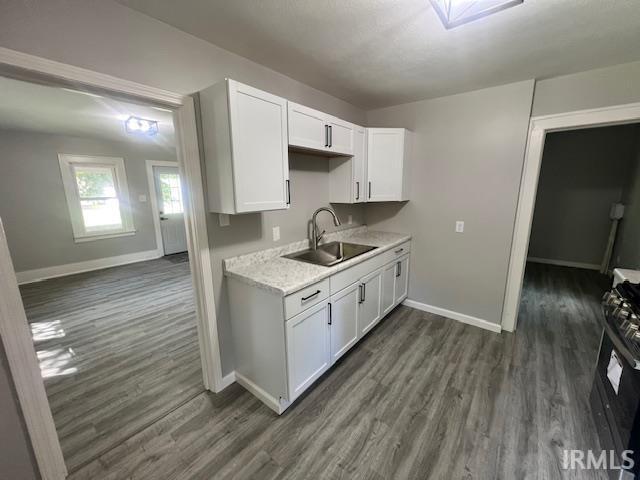 kitchen with sink, dark wood-type flooring, range with gas cooktop, and white cabinets