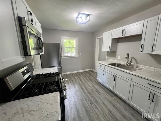 kitchen with stainless steel appliances, sink, and white cabinets