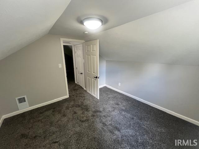 bonus room with vaulted ceiling and dark carpet