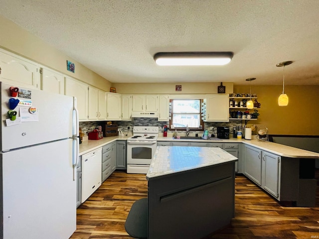 kitchen featuring dark hardwood / wood-style flooring, a textured ceiling, white appliances, and decorative light fixtures