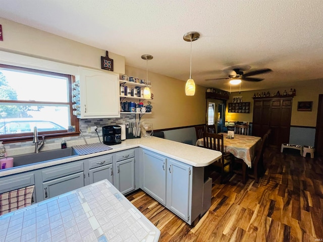 kitchen featuring sink, hardwood / wood-style flooring, tasteful backsplash, ceiling fan, and kitchen peninsula