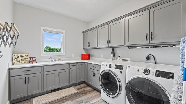 washroom with cabinets, washer and clothes dryer, sink, and wood-type flooring