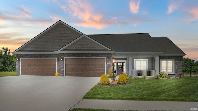 craftsman-style home featuring a garage, covered porch, and a lawn