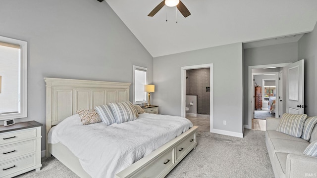 bedroom featuring ceiling fan, high vaulted ceiling, ensuite bath, and light colored carpet