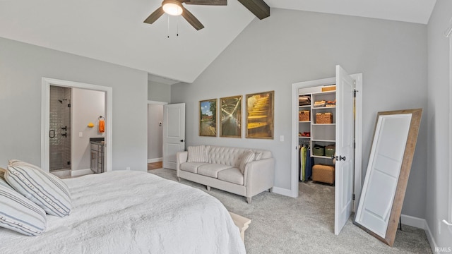 bedroom featuring ceiling fan, a walk in closet, ensuite bath, beamed ceiling, and carpet floors