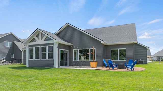 back of property with a lawn, a patio area, and a fire pit