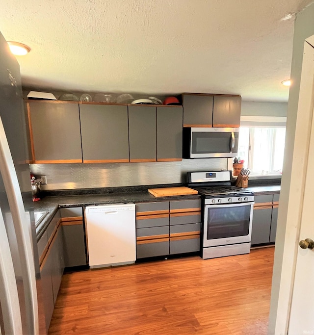 kitchen featuring appliances with stainless steel finishes, a textured ceiling, light wood-type flooring, and gray cabinetry