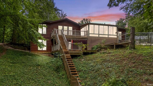 back house at dusk featuring a wooden deck