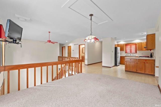 kitchen featuring light tile patterned floors, lofted ceiling, stainless steel refrigerator, ceiling fan, and sink