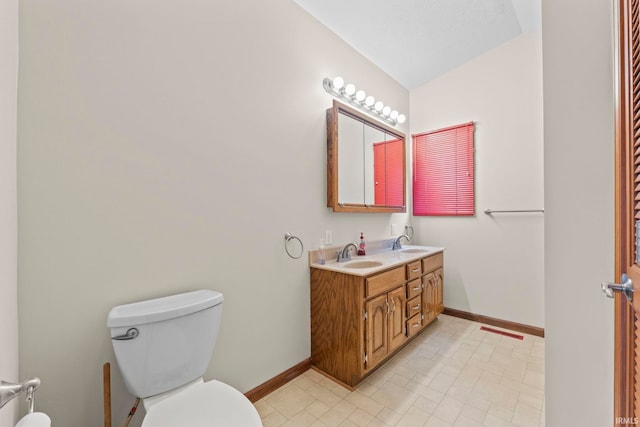 bathroom with double sink vanity, lofted ceiling, tile patterned flooring, and toilet