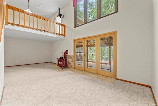 interior space with a towering ceiling, french doors, carpet, and a wealth of natural light