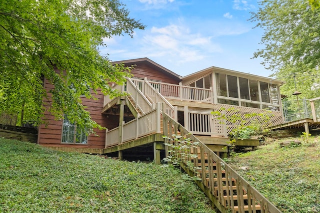 rear view of house featuring a sunroom and a deck