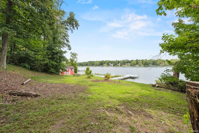 view of yard featuring a water view, a storage unit, and a boat dock