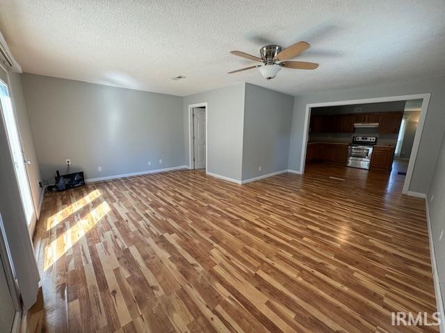 unfurnished living room with hardwood / wood-style floors, ceiling fan, and a textured ceiling