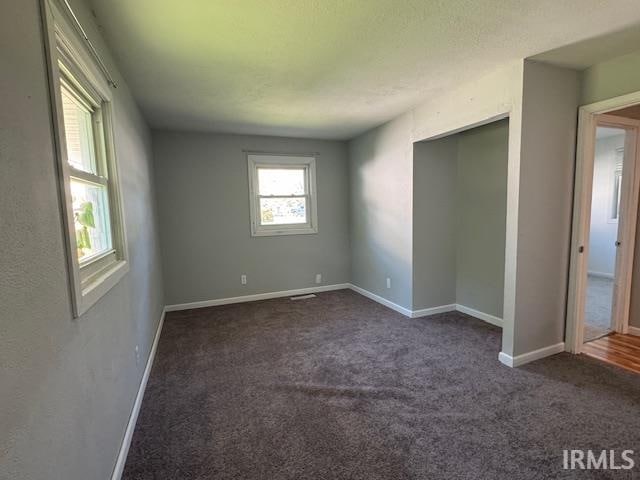 unfurnished bedroom with dark carpet