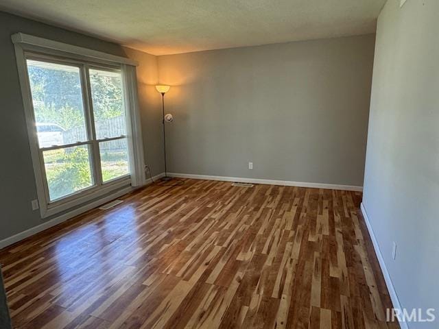 empty room featuring a healthy amount of sunlight and dark hardwood / wood-style flooring