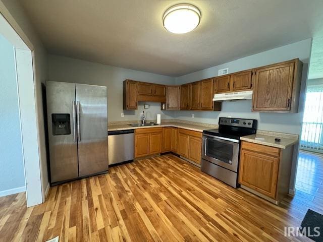 kitchen with appliances with stainless steel finishes, light hardwood / wood-style floors, and sink