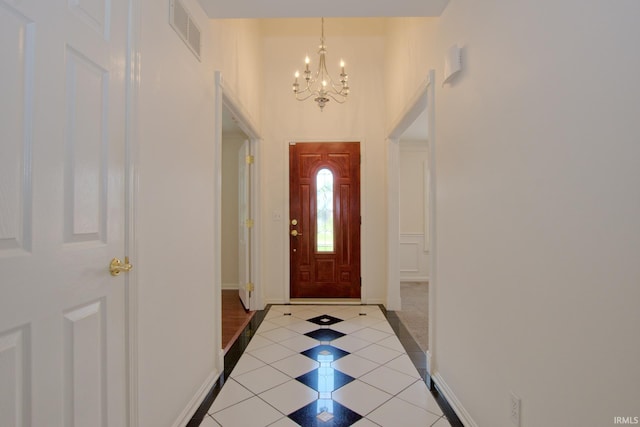 doorway with a notable chandelier and light tile patterned floors