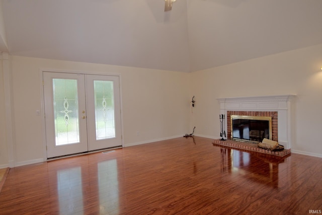 unfurnished living room with hardwood / wood-style floors, french doors, a fireplace, and lofted ceiling