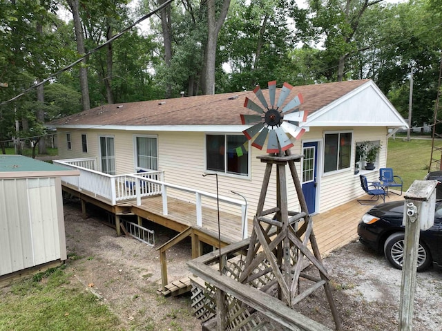 rear view of property with a shingled roof, an outdoor structure, and a wooden deck