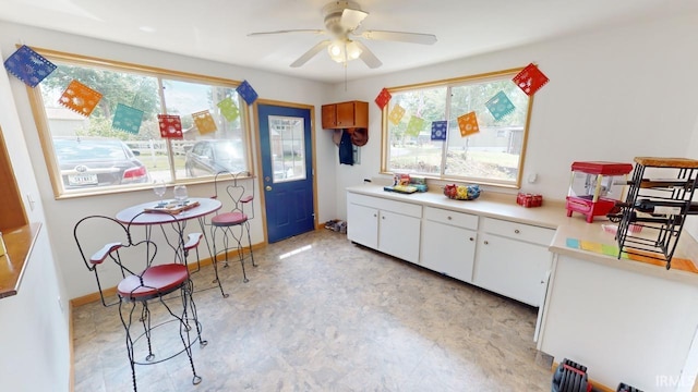 kitchen with light countertops, white cabinetry, a ceiling fan, and a healthy amount of sunlight