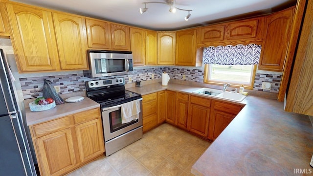 kitchen featuring appliances with stainless steel finishes, light countertops, a sink, and backsplash