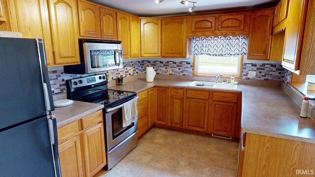 kitchen with appliances with stainless steel finishes, light tile patterned flooring, tasteful backsplash, and sink