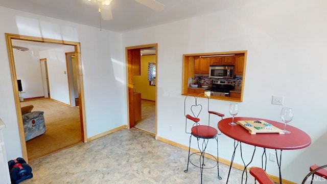 kitchen featuring appliances with stainless steel finishes, decorative backsplash, light colored carpet, and ceiling fan