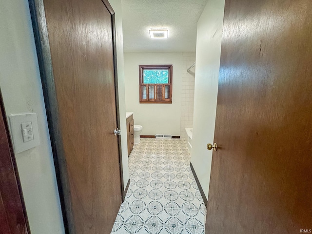 hall with light tile patterned flooring and a textured ceiling