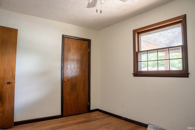 unfurnished bedroom featuring ceiling fan, light wood-type flooring, and a textured ceiling