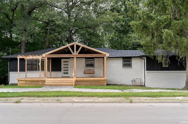 view of front of property featuring brick siding, covered porch, and a shingled roof