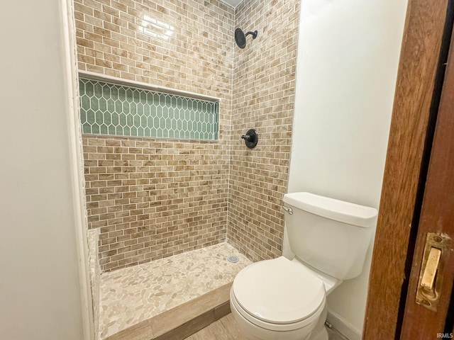 bathroom featuring tiled shower and toilet