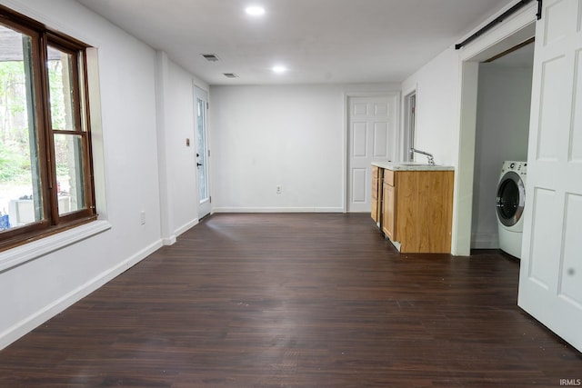 empty room featuring washer / clothes dryer, dark hardwood / wood-style floors, a barn door, and sink