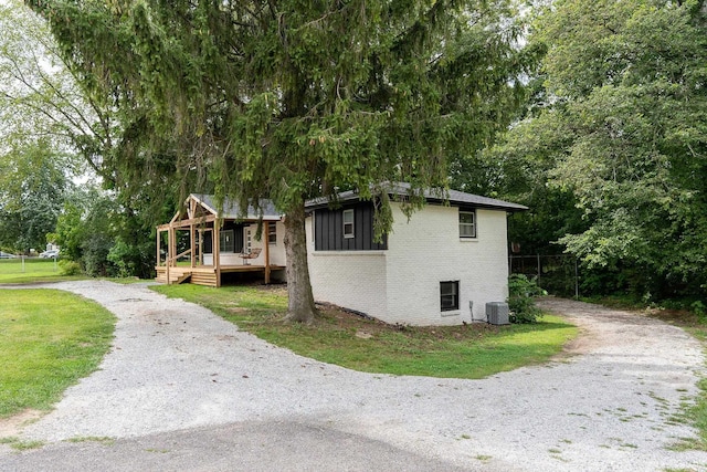 view of side of home featuring cooling unit and a yard