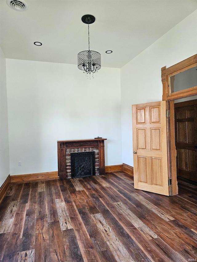 unfurnished living room with dark wood-type flooring and a brick fireplace