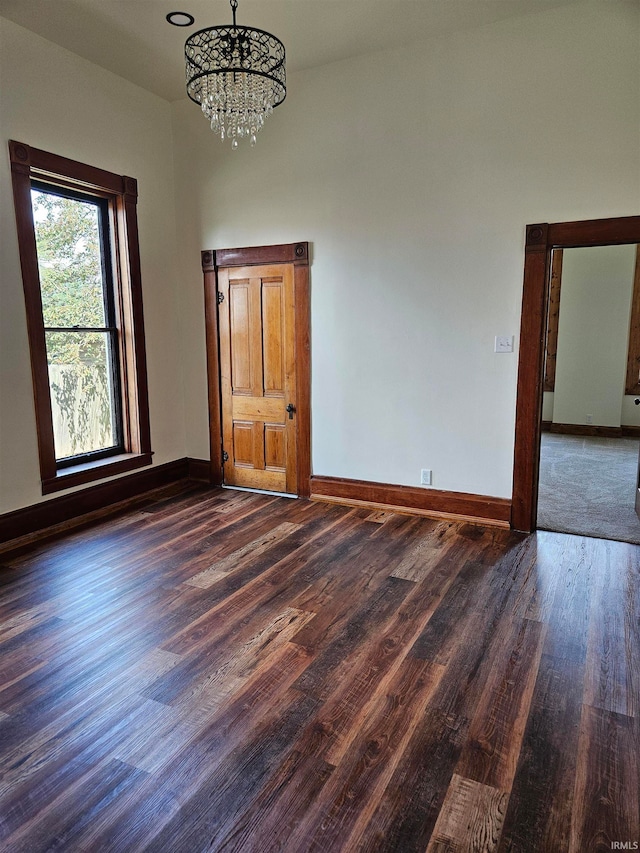 spare room featuring a notable chandelier and dark hardwood / wood-style flooring