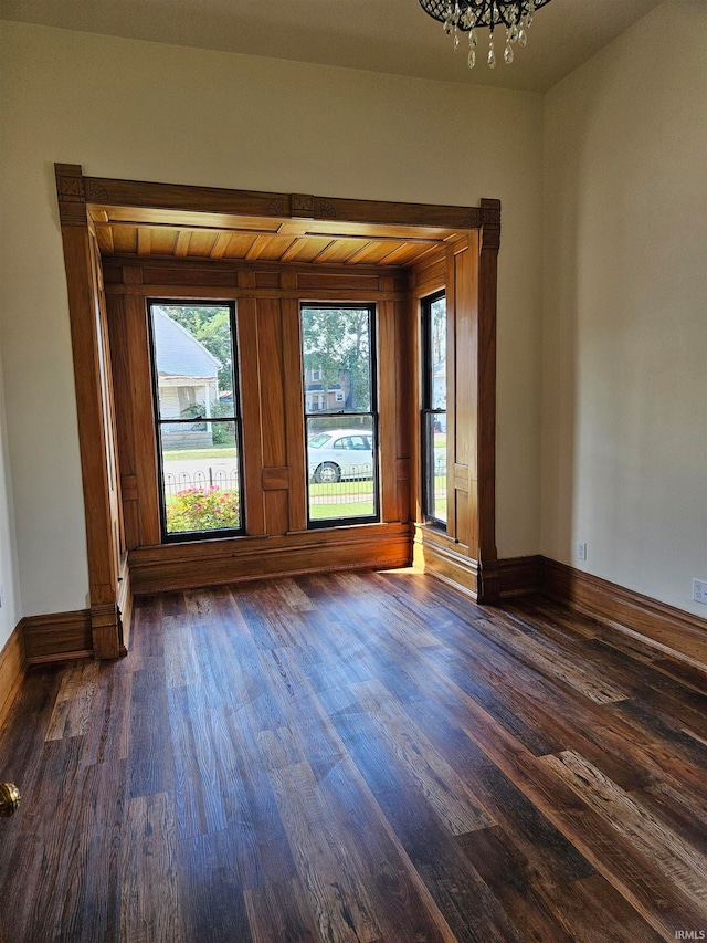 empty room featuring dark hardwood / wood-style floors and an inviting chandelier